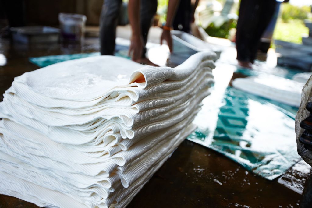 Mantas absorbentes industriales de polipropileno apiladas para contención de derrames en exterior.