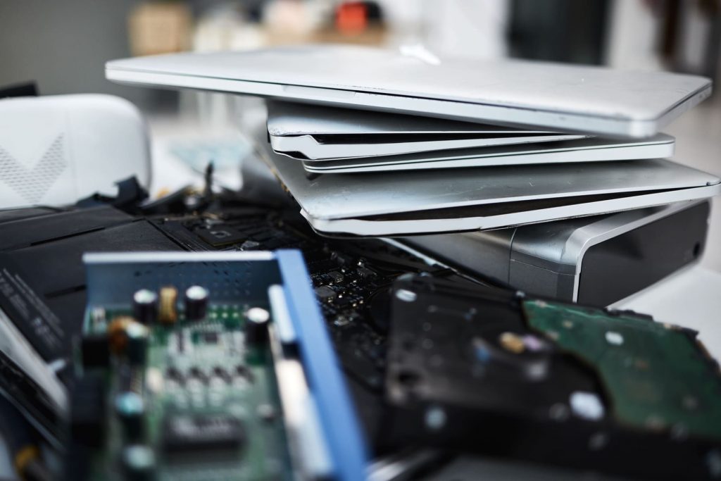 Portátiles y componentes electrónicos obsoletos apilados como residuos RAEE de empresa.