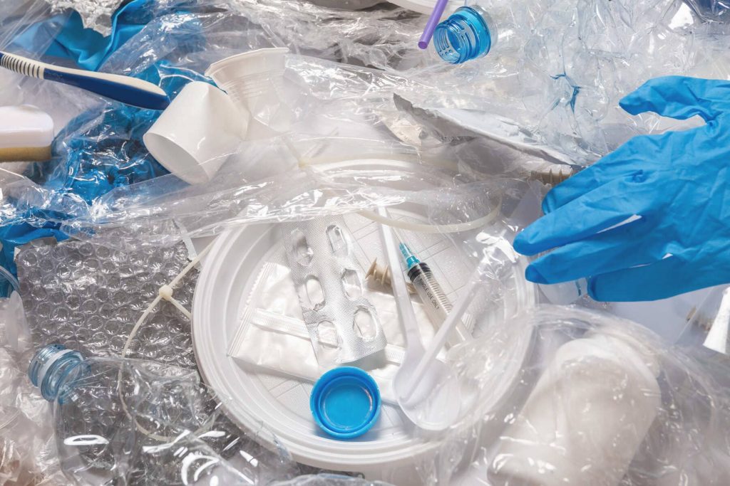 Clasificación de residuos peligrosos farmacéuticos: blísteres de medicamentos, botellas etiquetadas y envases plásticos contaminados durante el proceso de gestión en laboratorio.