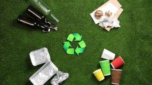 Símbolo de reciclaje rodeado de vidrio, papel, aluminio y vasos separados por tipo.